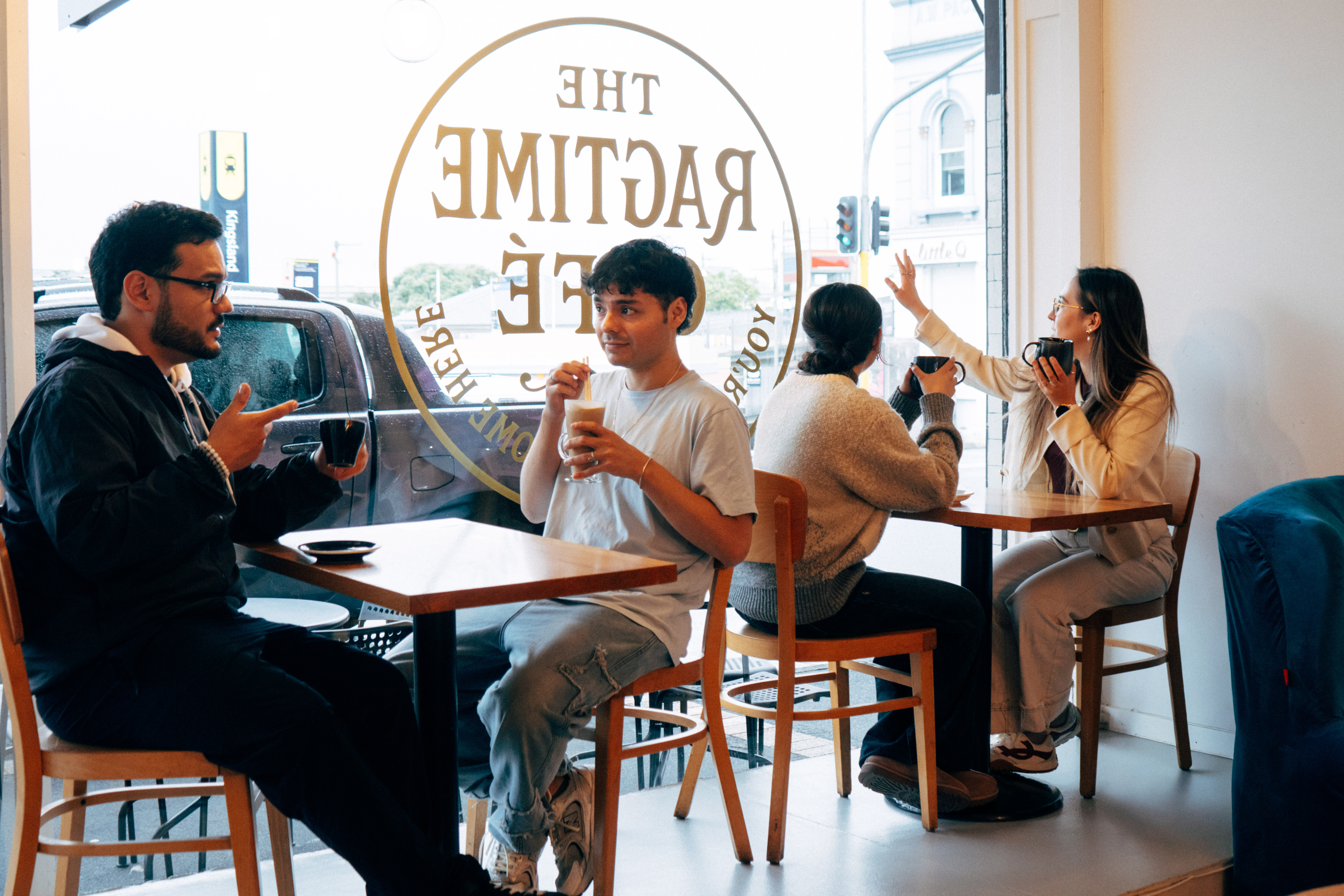 Friends enjoying drinks together by The Ragtime Café window